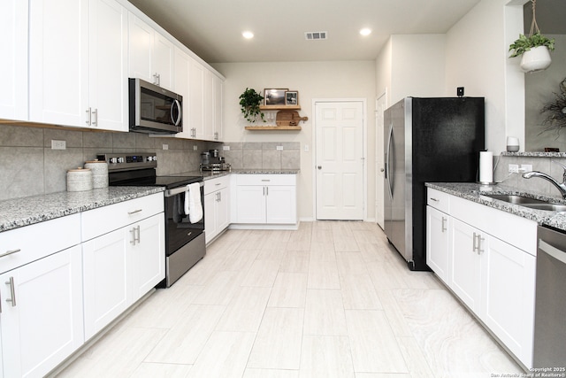 kitchen with stainless steel appliances, white cabinetry, a sink, and visible vents