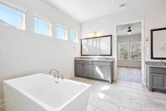 bathroom featuring two vanities, a freestanding tub, visible vents, and a sink