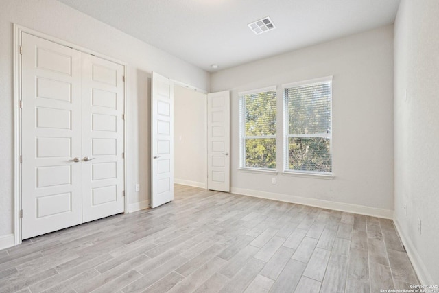 unfurnished bedroom featuring light wood-style flooring, visible vents, and baseboards