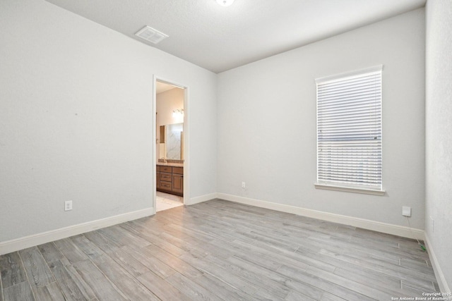 spare room with light wood-type flooring, baseboards, and visible vents