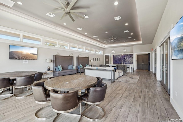 interior space with a ceiling fan, wood tiled floor, a raised ceiling, and visible vents