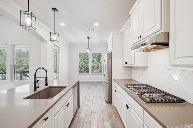 kitchen with stone countertops, under cabinet range hood, a sink, white cabinets, and appliances with stainless steel finishes