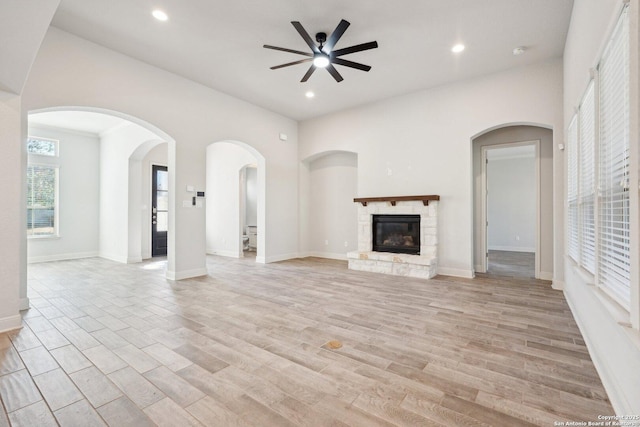 unfurnished living room featuring light wood finished floors, recessed lighting, baseboards, and a stone fireplace