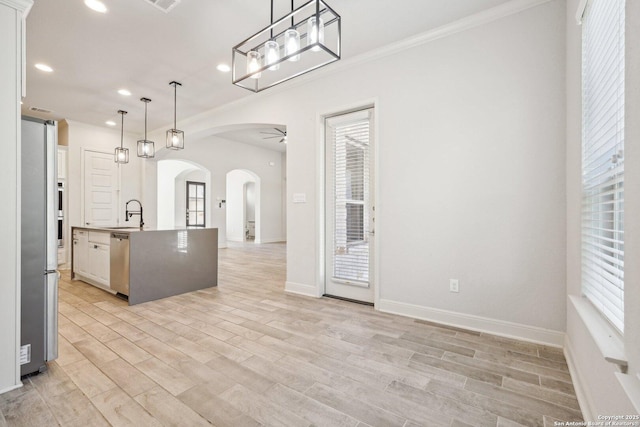 kitchen featuring stainless steel appliances, arched walkways, pendant lighting, and white cabinetry