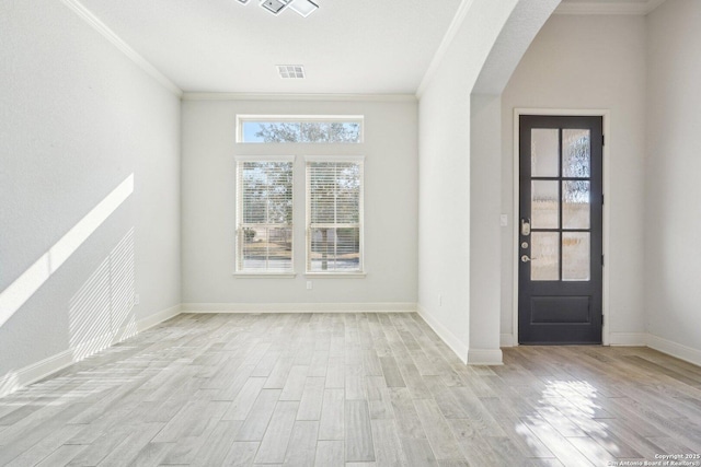 foyer entrance with arched walkways, crown molding, light wood finished floors, visible vents, and baseboards