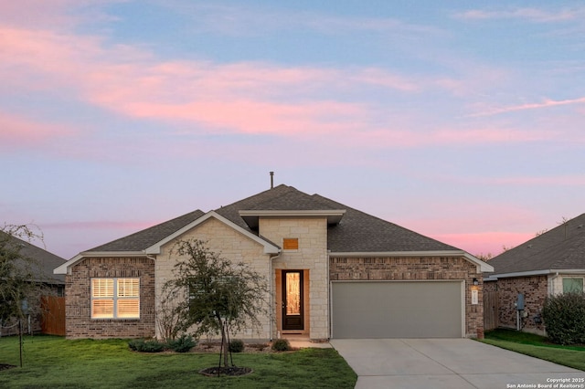 view of front of home featuring driveway, roof with shingles, an attached garage, a front lawn, and brick siding