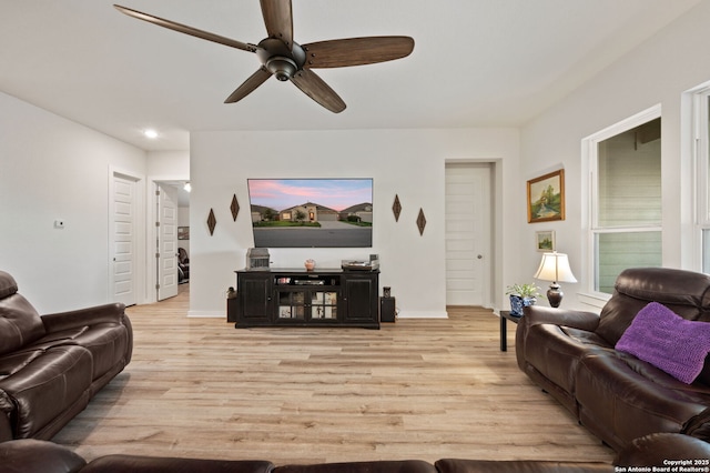 living area with a ceiling fan, baseboards, and light wood finished floors