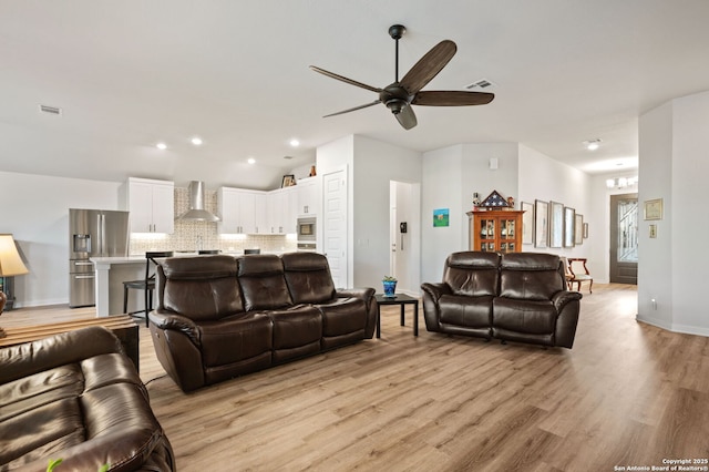 living room featuring recessed lighting, visible vents, light wood finished floors, and ceiling fan with notable chandelier