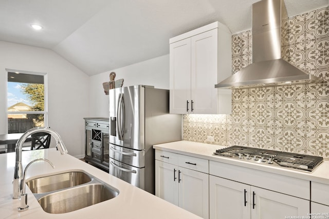 kitchen featuring stainless steel appliances, light countertops, white cabinetry, a sink, and wall chimney range hood