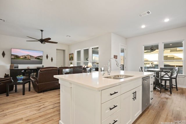 kitchen with visible vents, white cabinets, open floor plan, light countertops, and a center island with sink