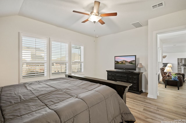 bedroom with lofted ceiling, light wood-style flooring, visible vents, and a ceiling fan