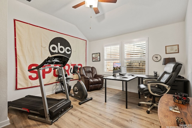 interior space with vaulted ceiling, wood finished floors, a ceiling fan, and baseboards