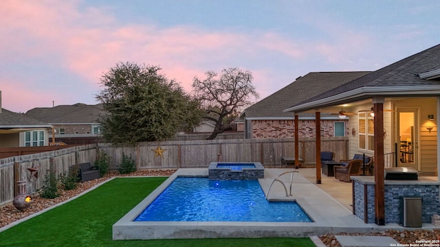 pool at dusk with a yard, a patio area, a fenced backyard, and a pool with connected hot tub