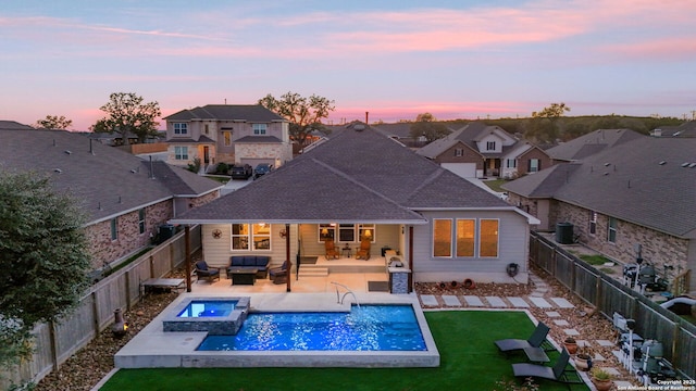 back of house at dusk featuring a fenced backyard, a residential view, outdoor lounge area, and a lawn