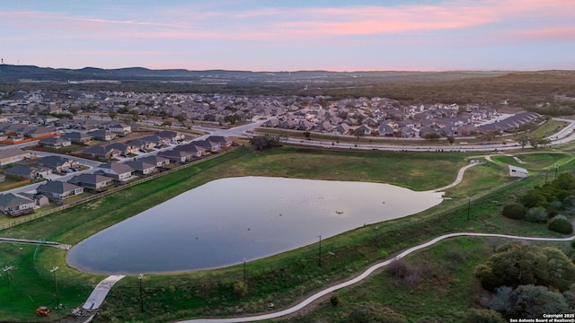 aerial view at dusk with a water view and a residential view