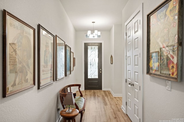 entrance foyer featuring a chandelier, light wood-style flooring, and baseboards