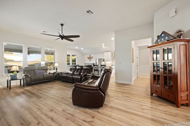 living area featuring vaulted ceiling, ceiling fan, light wood finished floors, and visible vents