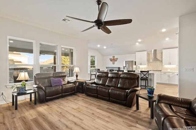 living room with vaulted ceiling, ceiling fan, light wood finished floors, and visible vents