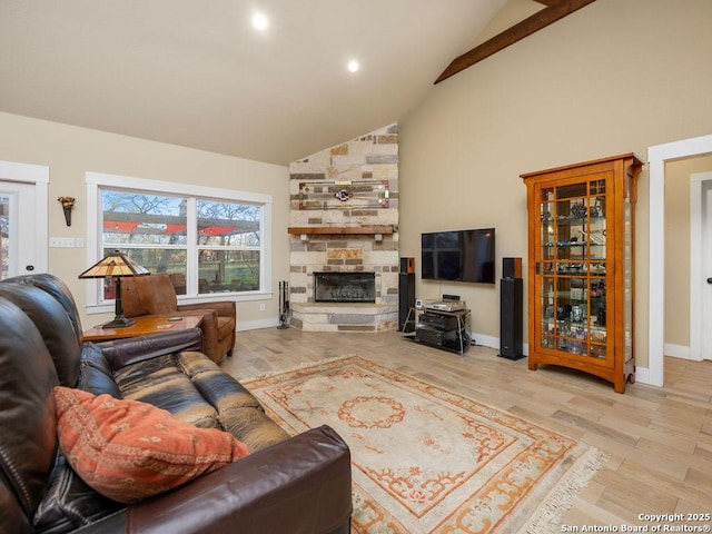 living area with light wood-style floors, high vaulted ceiling, and a stone fireplace