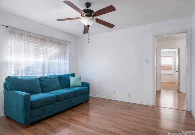 living area with ceiling fan, baseboards, and wood finished floors