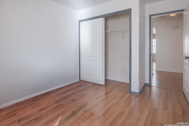 unfurnished bedroom with a closet, wood finished floors, and baseboards