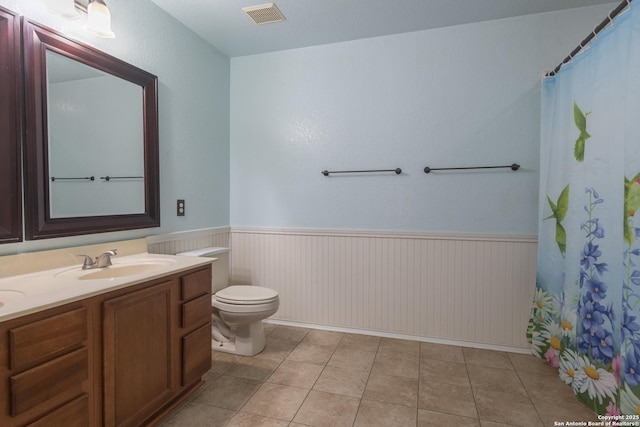 full bathroom featuring a wainscoted wall, toilet, vanity, and visible vents