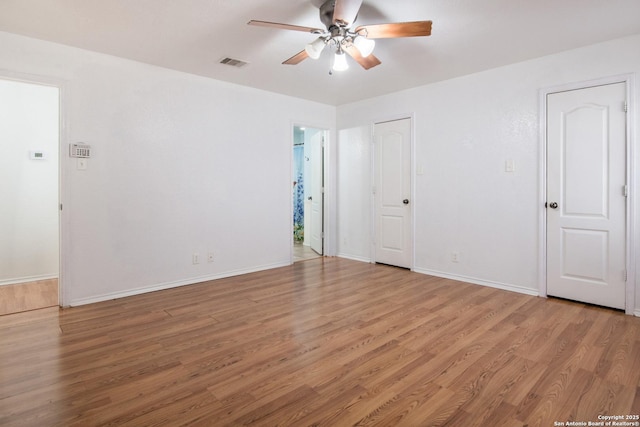 spare room featuring light wood-type flooring, ceiling fan, visible vents, and baseboards