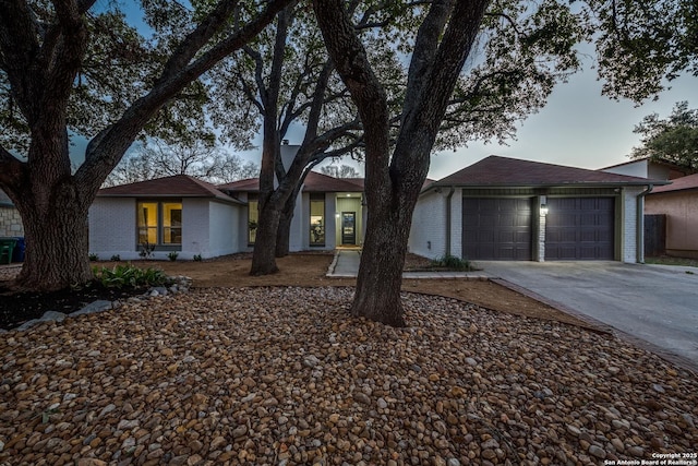 view of front facade with a garage, brick siding, and driveway