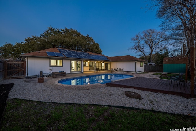 pool at dusk featuring a deck, a patio area, a fenced backyard, and a fenced in pool