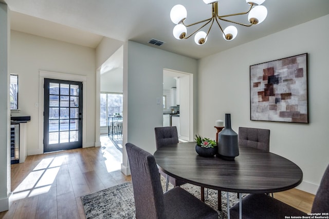 dining area featuring beverage cooler, visible vents, baseboards, light wood-style flooring, and an inviting chandelier