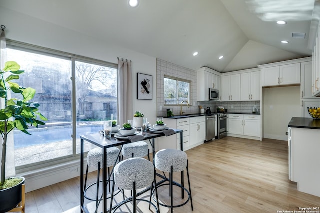 kitchen featuring appliances with stainless steel finishes, dark countertops, white cabinets, and visible vents