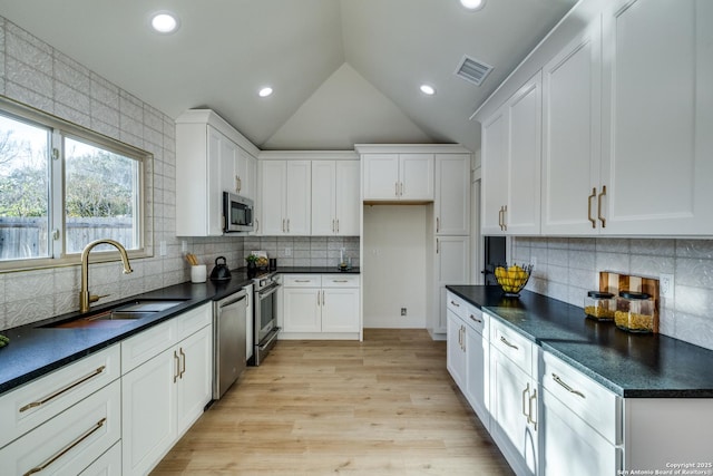 kitchen with stainless steel appliances, dark countertops, white cabinets, and visible vents