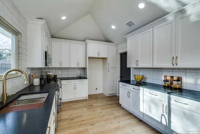 kitchen with dark countertops, white cabinetry, and a sink