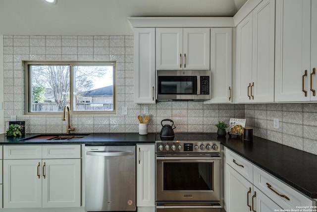 kitchen with tasteful backsplash, white cabinets, dark countertops, stainless steel appliances, and a sink