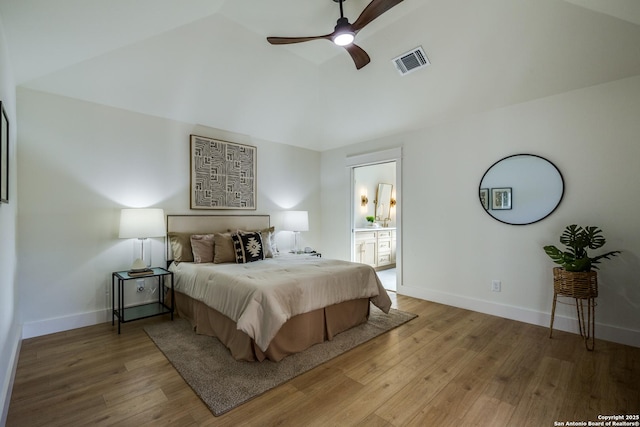 bedroom featuring visible vents, baseboards, vaulted ceiling, light wood-style floors, and ensuite bath