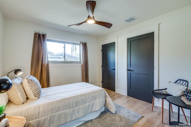 bedroom with light wood finished floors, visible vents, and a ceiling fan