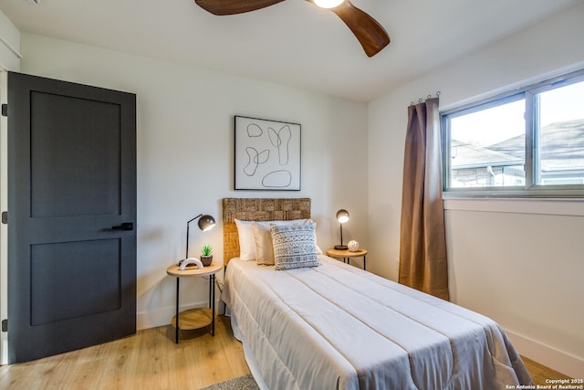 bedroom with ceiling fan, light wood-style flooring, and baseboards