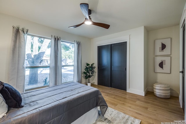 bedroom with light wood finished floors, a ceiling fan, baseboards, and a closet