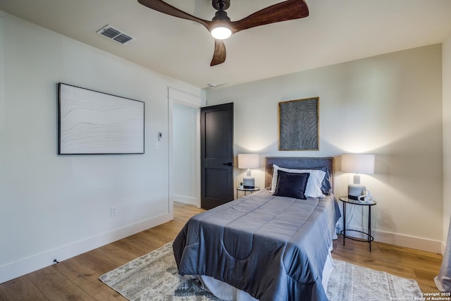 bedroom with light wood finished floors, baseboards, visible vents, and a ceiling fan