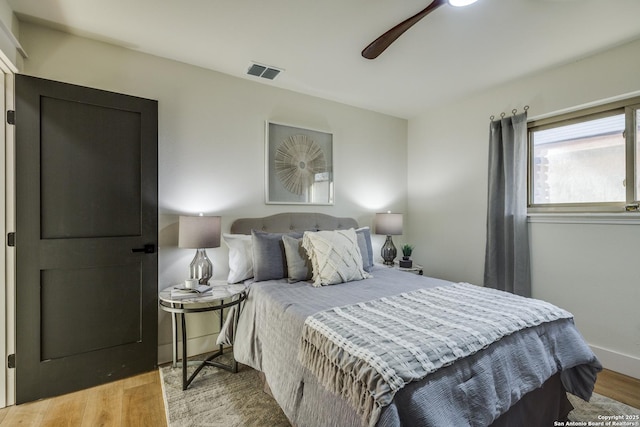 bedroom featuring visible vents, ceiling fan, baseboards, and wood finished floors