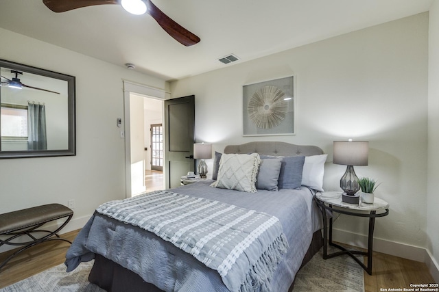 bedroom with a ceiling fan, wood finished floors, visible vents, and baseboards