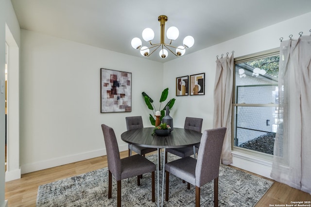 dining area featuring a chandelier, baseboards, and light wood finished floors