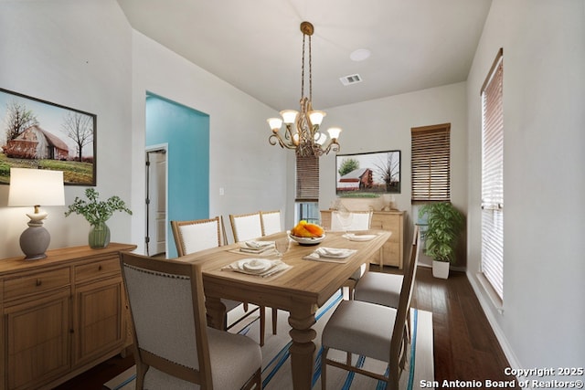 dining space with baseboards, dark wood-style flooring, visible vents, and an inviting chandelier