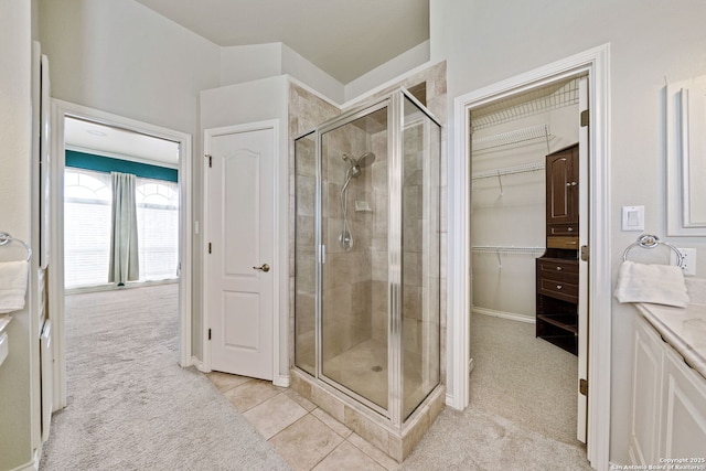 bathroom featuring a stall shower, a walk in closet, vanity, and tile patterned floors