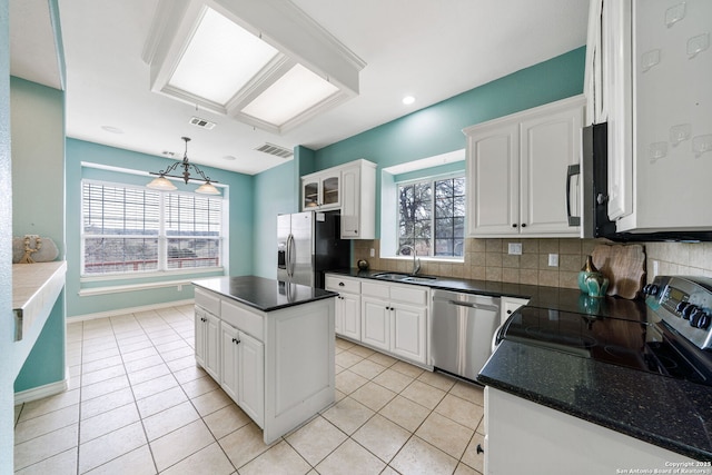 kitchen featuring stainless steel appliances, a sink, white cabinetry, a center island, and decorative light fixtures