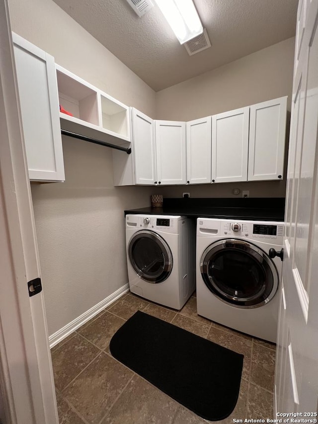 laundry area with cabinet space, a textured ceiling, baseboards, and washer and dryer