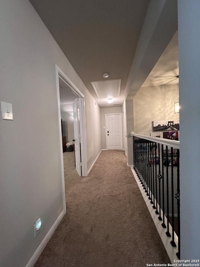 hallway with attic access, baseboards, and carpet flooring