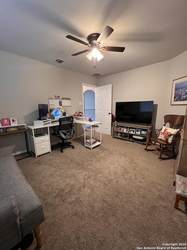 office with visible vents, dark carpet, and a ceiling fan