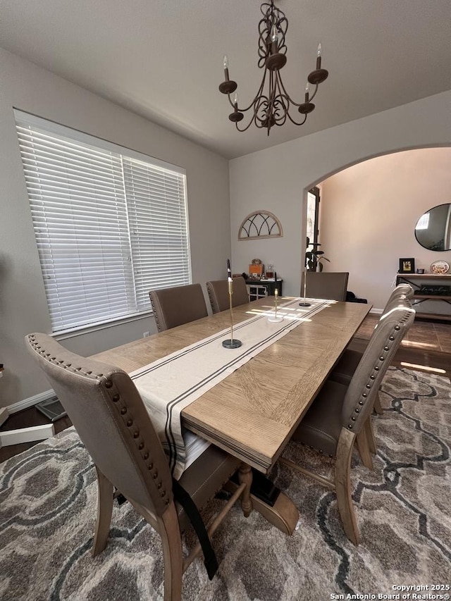 dining space with baseboards, arched walkways, and a notable chandelier