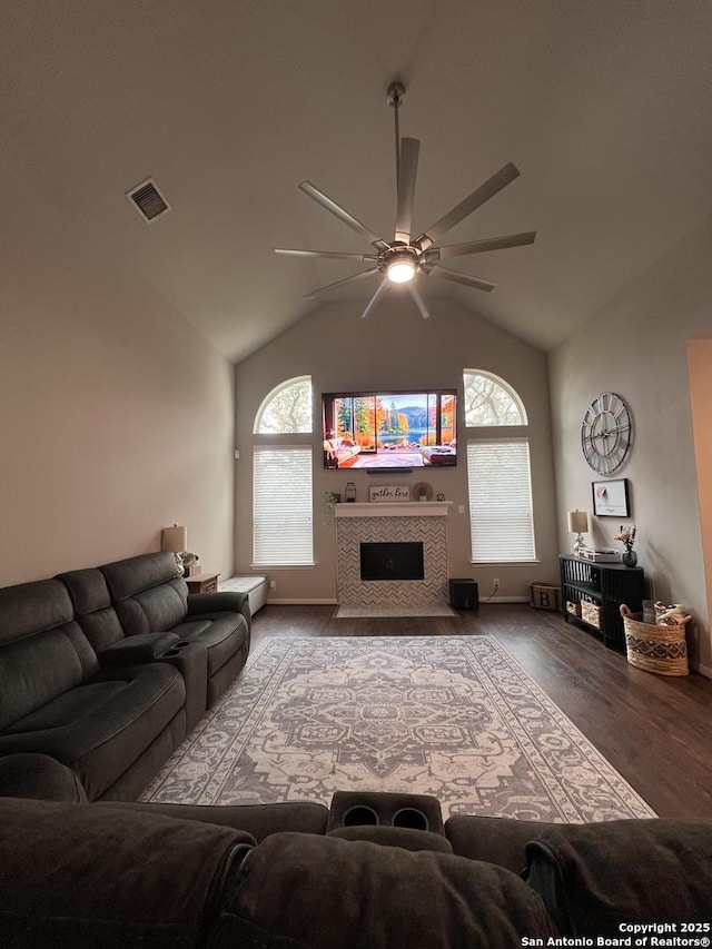 living area featuring a ceiling fan, a tile fireplace, high vaulted ceiling, and wood finished floors